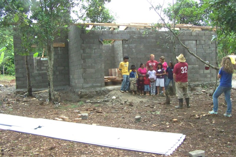 100_3581.JPG - House close to finsih with tin for roof on ground.